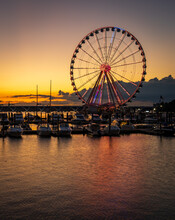 Illuminated Ferris Wheel At National Harbor Near The Nation Capital Of Washington DC At Sunset With Marina In The Foreground