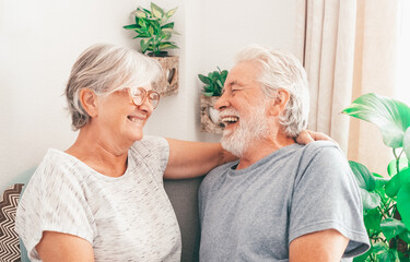 Wall Mural - Portrait of cheerful white-haired senior family couple laughing sitting at home.  Happy elderly man and woman embracing having fun together