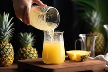 Woman Pouring Pineapple Juice From Jug Into Glass.