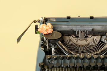 Wall Mural - Vintage typewriter with carnation flower on yellow background, closeup