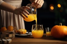 Woman Pouring Pumpkin Juice From Jug Into Glass.