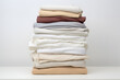Neatly folded clothes stacked on a wooden surface against a white backdrop