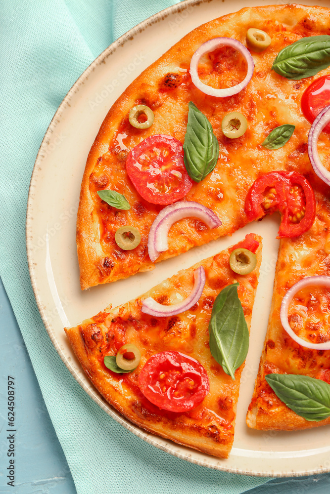 Plate with tasty pizza and towel on blue background