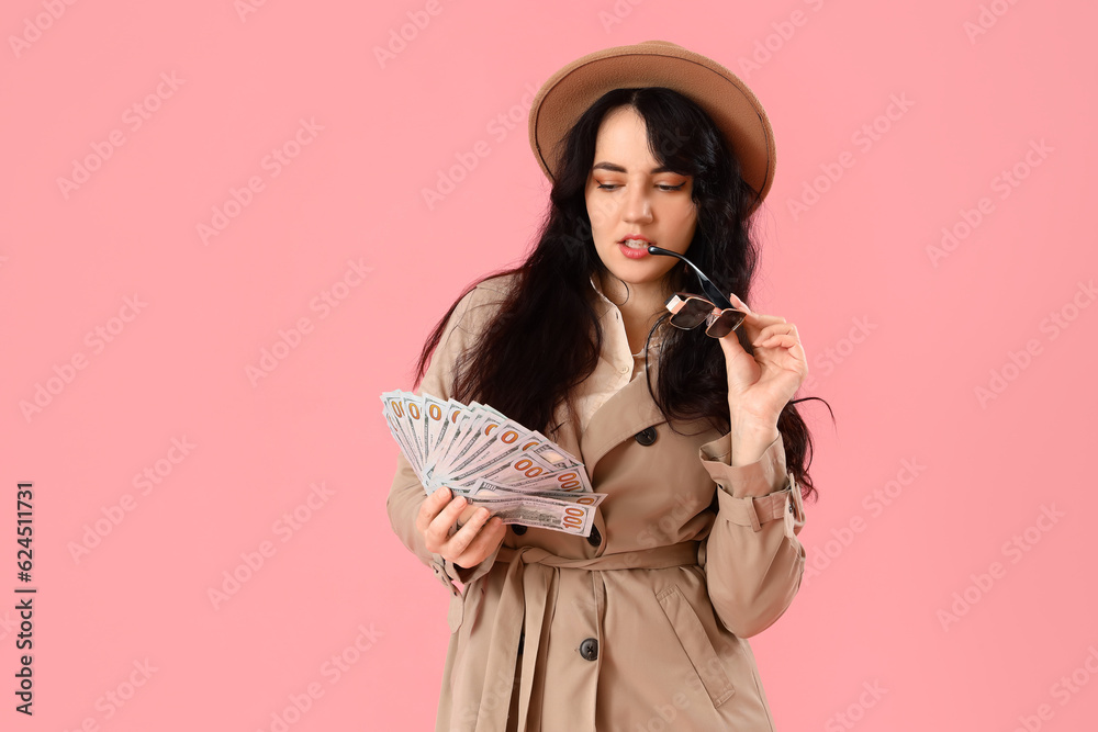 Thoughtful young woman with money on pink background