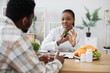 © Sofiia Shunkina - Focus on african american female in lab coat holding green fruit while staying in doctor's workplace. Serious medical specialist discussing benefits of avocado in healthy diet with attentive man.