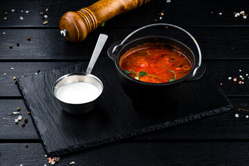 Wall Mural - Solyanka soup with ham, meat, olives, tomatoes, sour cream and microgreens in a bowl.