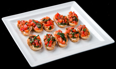 Canvas Print - Bruschetta with with tomatoes and herbs in a white plate.