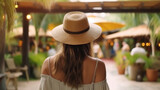 Fototapeta Uliczki - Back view of woman wearing hat at poolside on a tropical resort