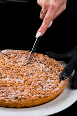 Wall Mural - The process of cutting crumbly pie with chocolate and powdered sugar.