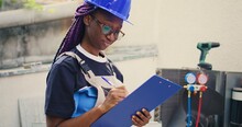 Portrait Shot Of Smiling African American Expert Doing Inspection Of Refrigerant Levels And Necessary Repairs To Prevent Major Breakdowns. Worker Checking Hvac System, Writing Findings On Clipboard