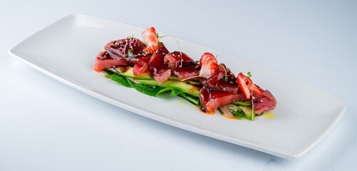 Wall Mural - Cold appetizer carpaccio with tuna, avocado, algae, strawberries, spinach, sesame seeds and sauce.