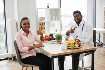 Sticker - Full length portrait of multicultural people posing at office desk in doctor's workplace of medical center. Attractive woman in casual wear visiting professional dietitian, showing thumbs up