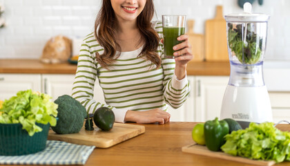 Portrait of beauty healthy asian woman making green vegetables detox cleanse and green fruit smoothie with blender.young girl drinking glass of smoothie, fiber, chlorophyll in kitchen.Diet, healthy