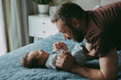 © Cavan Images - Dad is talking to the baby on the bed holding his hands