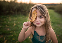Little Girl Playing With Orange Leaves