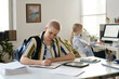 © Mediaphotos - Young woman sitting at table and filling documents in bureaucracy office