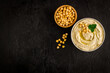 Bowl of chickpeas hummus with oil and herbs, top view
