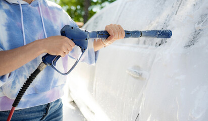 Wall Mural - Girl washing a white car in a self-service car wash station. Wash car self-service station.