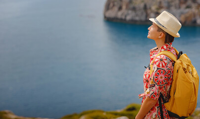 Wall Mural - Asian woman in hat look on views of azure Bay in Mediterranean sea. Travel and vacation concept. Anthony Quinn bay with crystal clear water in Rhodes island, Greece. The most beautiful beach.