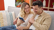 © Krakenimages.com - Man and woman couple using smartphone sitting on sofa at home