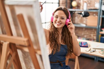 Wall Mural - Young beautiful hispanic woman artist listening to music drawing at art studio