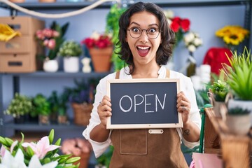 Sticker - Young hispanic woman working at florist holding open sign afraid and shocked with surprise and amazed expression, fear and excited face.