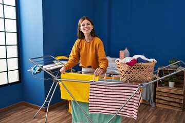 Poster - Young blonde woman smiling confident hanging clothes on clothesline at laundry room