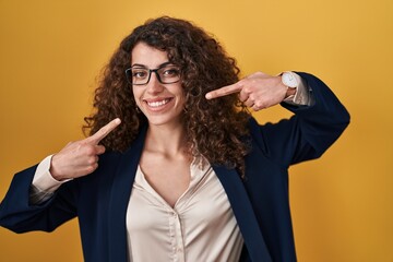 Sticker - Hispanic woman with curly hair standing over yellow background smiling cheerful showing and pointing with fingers teeth and mouth. dental health concept.