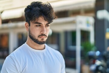 Wall Mural - Young hispanic man with relaxed expression standing at street