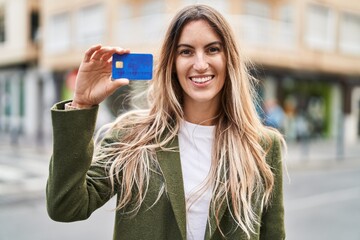 Wall Mural - Young woman smiling confident holding credit card at street