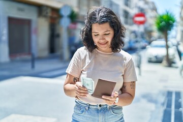 Young woman smiling confident counting dollars at street