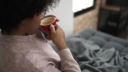 Poster - Young african american woman drinking tea sitting on sofa at home