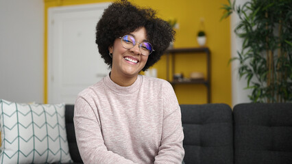 Poster - Young african american woman smiling sitting on sofa at home