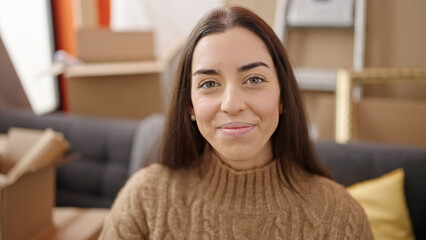 Canvas Print - Young beautiful hispanic woman smiling confident sitting on sofa at new home