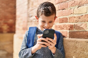 Wall Mural - Blond child student using smartphone standing at street