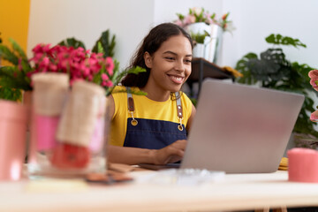 Canvas Print - Young african american woman florist smiling confident using laptop at flower shop