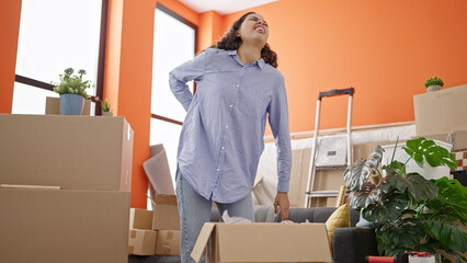 Sticker - Young beautiful hispanic woman moving box with back ache at new home