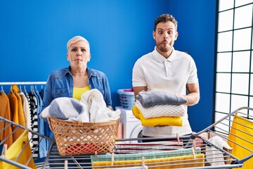 Poster - Hispanic mother and son hanging clothes at clothesline making fish face with mouth and squinting eyes, crazy and comical.