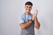 © Krakenimages.com - Hispanic young man wearing apron over white background clapping and applauding happy and joyful, smiling proud hands together