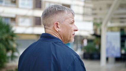 Wall Mural - Middle age grey-haired man standing with serious expression at street