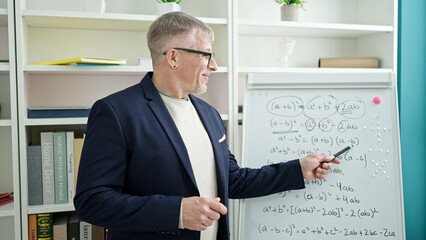 Wall Mural - Middle age grey-haired man teacher teaching maths lesson at university classroom