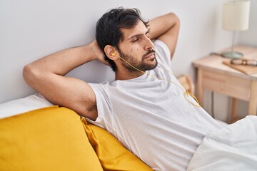 Sticker - Young hispanic man listening to music relaxed on bed at bedroom