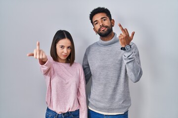 Wall Mural - Young hispanic couple standing together showing middle finger, impolite and rude fuck off expression