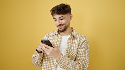 Sticker - Young arab man smiling confident using smartphone over isolated yellow background