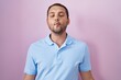 © Krakenimages.com - Hispanic man standing over pink background making fish face with lips, crazy and comical gesture. funny expression.