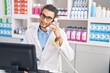 © Krakenimages.com - Young hispanic man pharmacist talking on telephone using computer at pharmacy