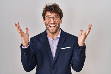 Poster - Hispanic business man wearing glasses celebrating crazy and amazed for success with arms raised and open eyes screaming excited. winner concept