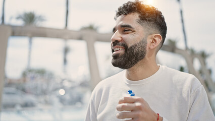 Sticker - Young hispanic man smiling confident holding bottle of water at street