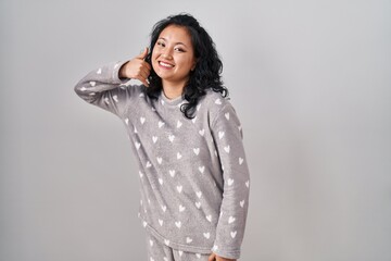 Sticker - Young asian woman wearing pajama smiling doing phone gesture with hand and fingers like talking on the telephone. communicating concepts.