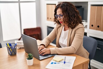 Wall Mural - Middle age hispanic woman working with laptop at the office